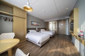 Habitación de hotel con dos camas, piso de madera, un escritorio y una silla.