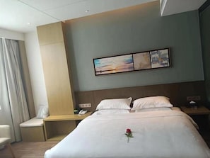A hotel room with a bed, bedside tables, a desk, and a chair.