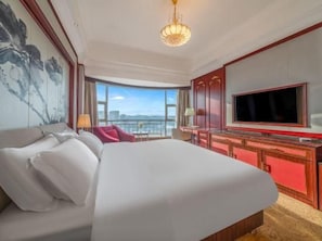 Habitación de hotel con una cama grande, televisión, escritorio con silla y vista al exterior.