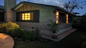 Uma casa com fachada de pedra, chaminé e janela bem iluminada.