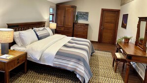 Quarto com cama, mesas de cabeceira, cômoda, escrivaninha e espelho.