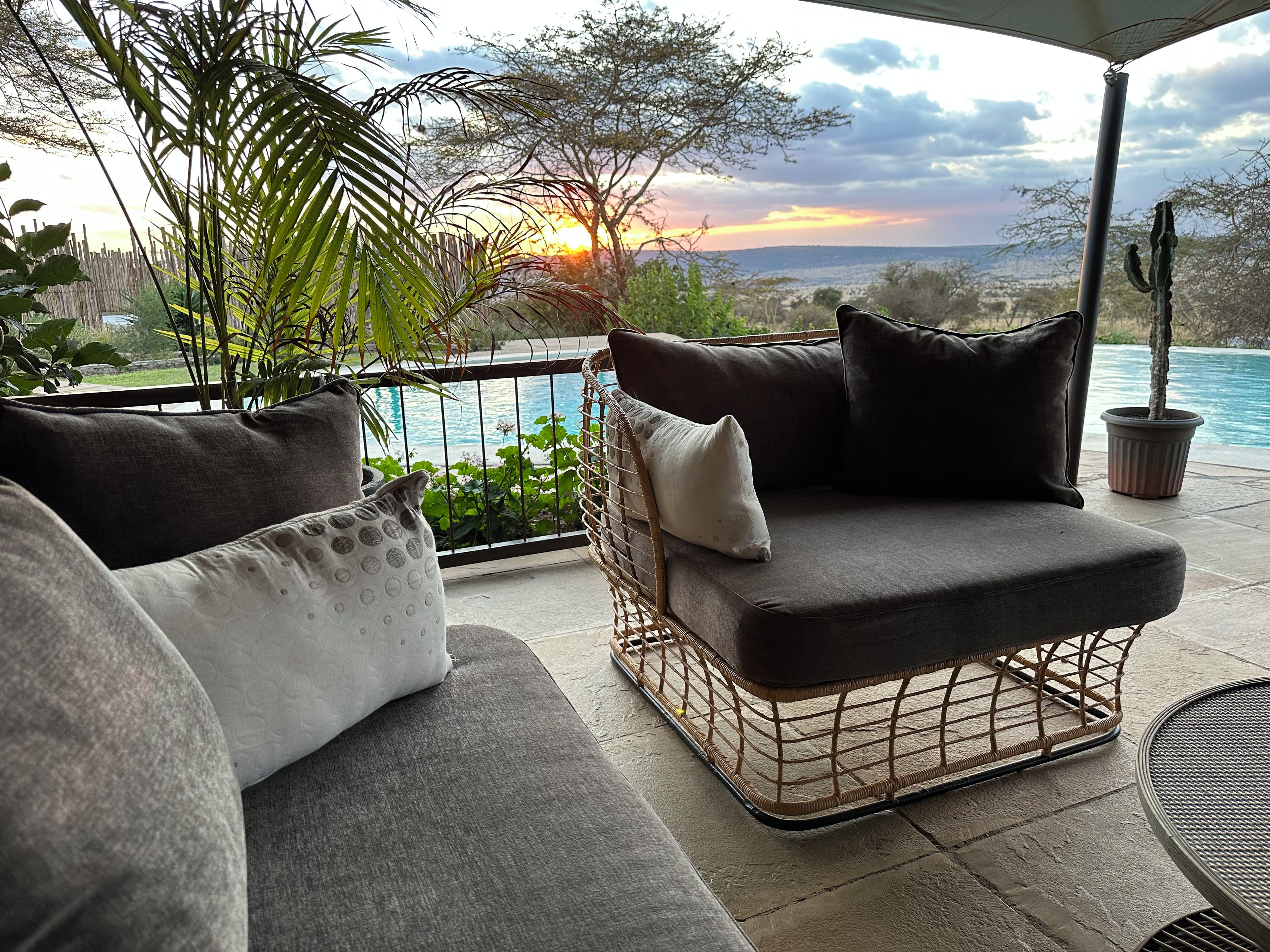 A patio with a cushioned seating area, a pool, and a view of the landscape.