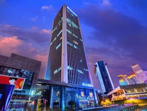 A high-rise building with a modern design, featuring a prominent vertical structure and illuminated windows. - Lavande Hotel (Chongqing)