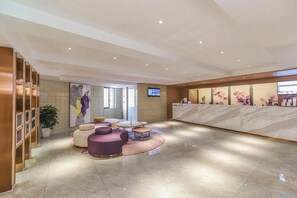 A modern lobby with a reception desk, seating area, and a large artwork on the wall. - Lavande Hotel (Chongqing)