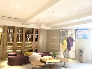 A modern interior with seating areas, a wall-mounted artwork, and informational posters. - Lavande Hotel (Chongqing)