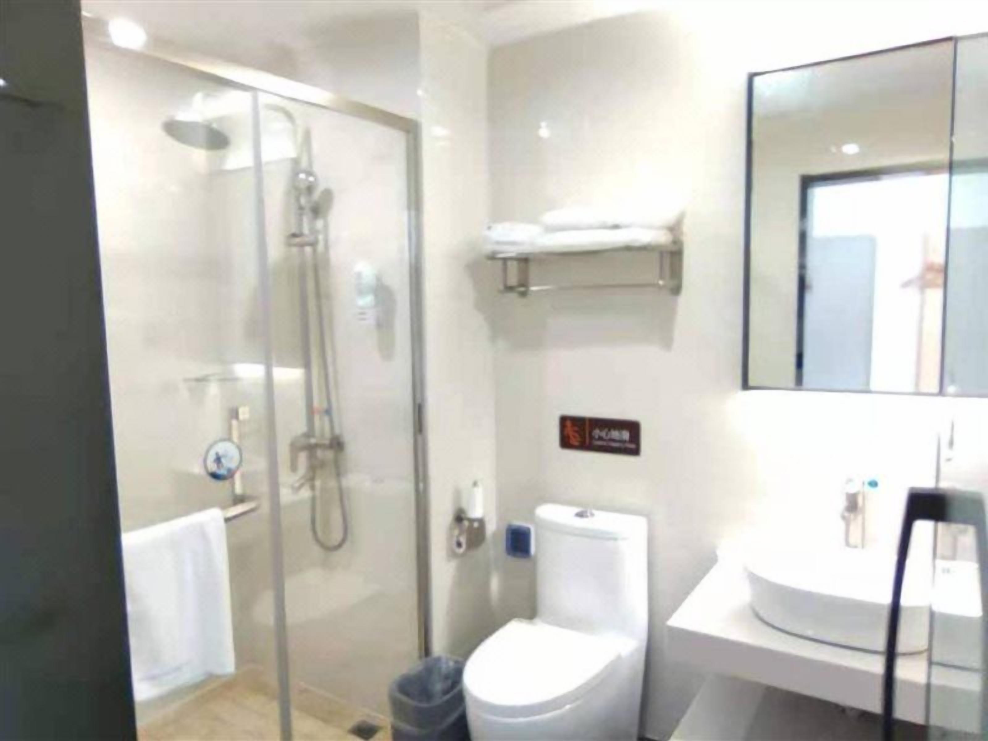 A modern bathroom with a glass-enclosed shower, a toilet, and a sink.