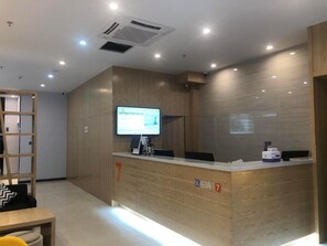 A reception desk with a flat-screen monitor, a small desk lamp, and a digital scale. - 7 Premium Hotel (Huai'an)