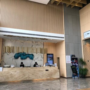 A reception desk with a modern design, featuring a marble wall and a hanging decorative piece. - Atour Hotel Suzhou Industrial Park, Fashion Stage (Suzhou)