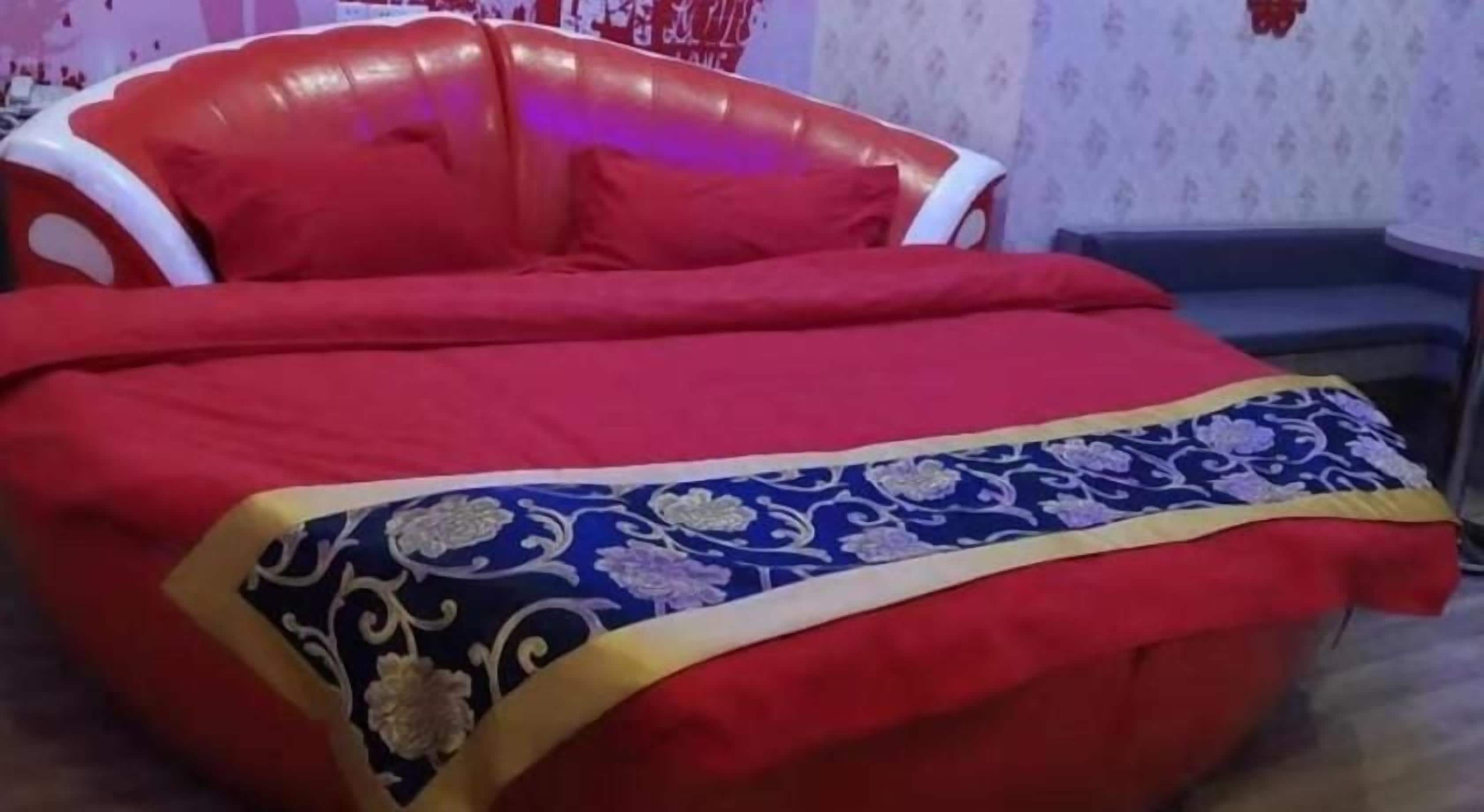 Un canapé-lit rouge avec un revêtement à motifs, une petite table et une chaise.