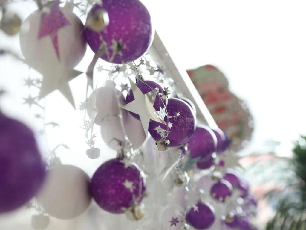 A close-up of a Christmas tree with purple ornaments and star-shaped decorations.