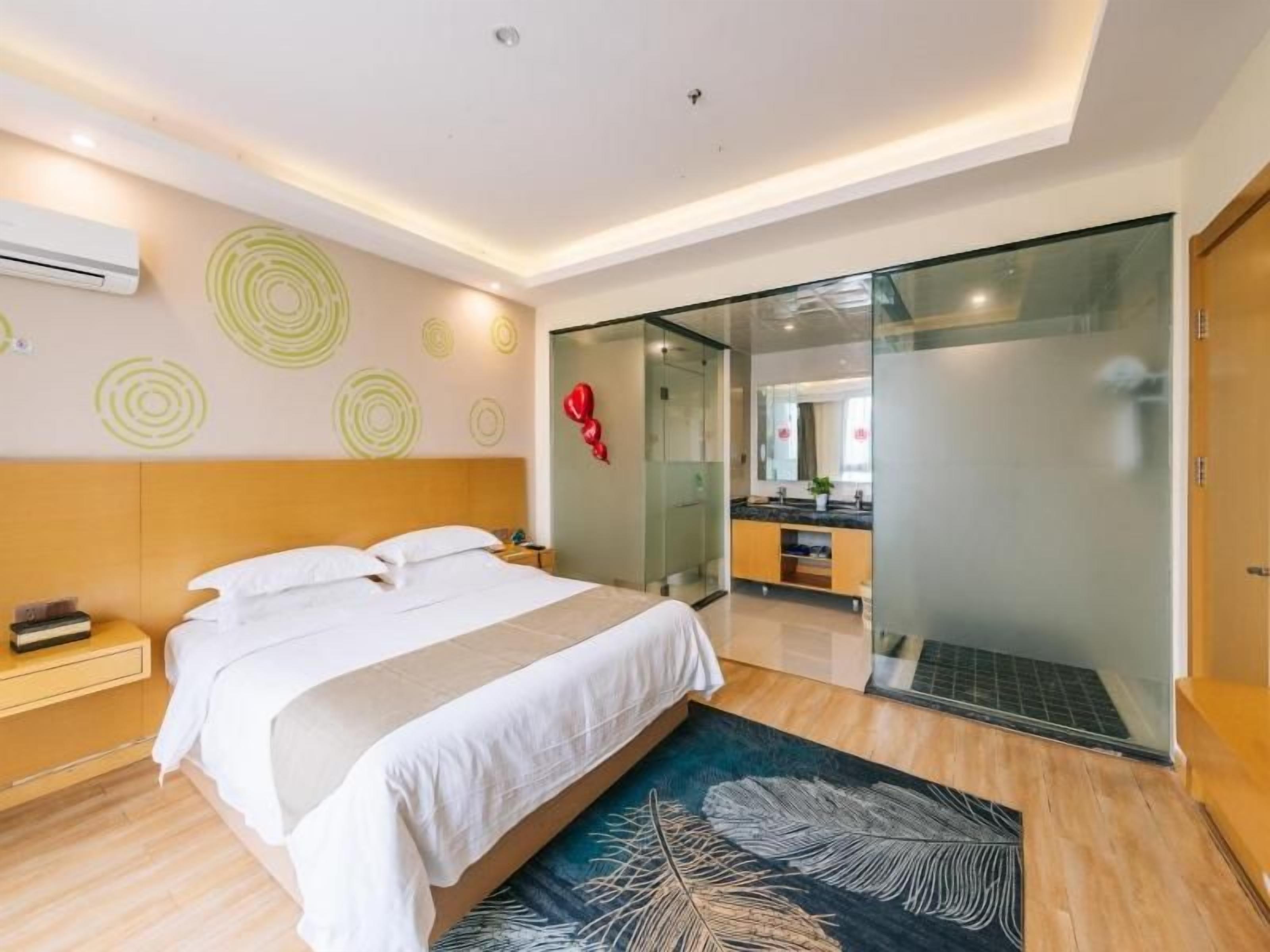 A modern hotel room with a large bed, a glass shower enclosure, and a visible bathroom.