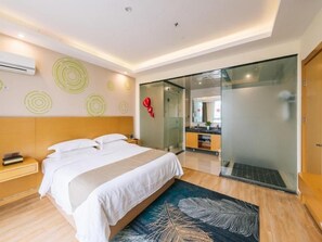 Ein modernes Hotelzimmer mit einem großen Bett, einer Duschkabine aus Glas und einem sichtbaren Badezimmer.