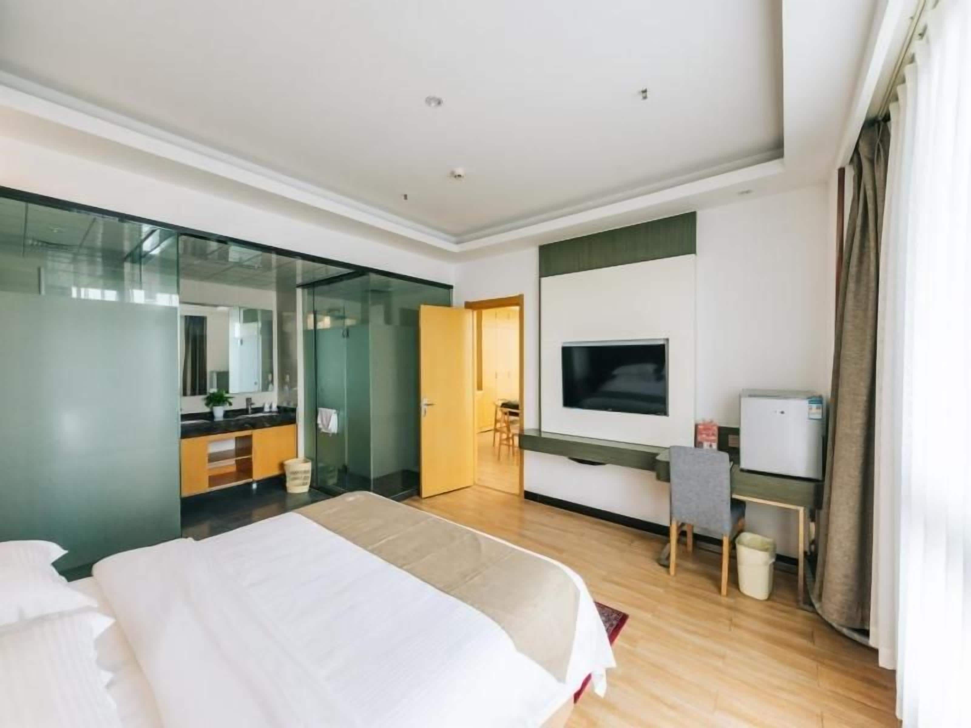 A hotel room with a bed, a television, a desk, and a mirror.