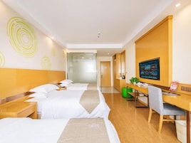 Quarto de hotel com duas camas, uma escrivaninha, uma cadeira e uma televisão.