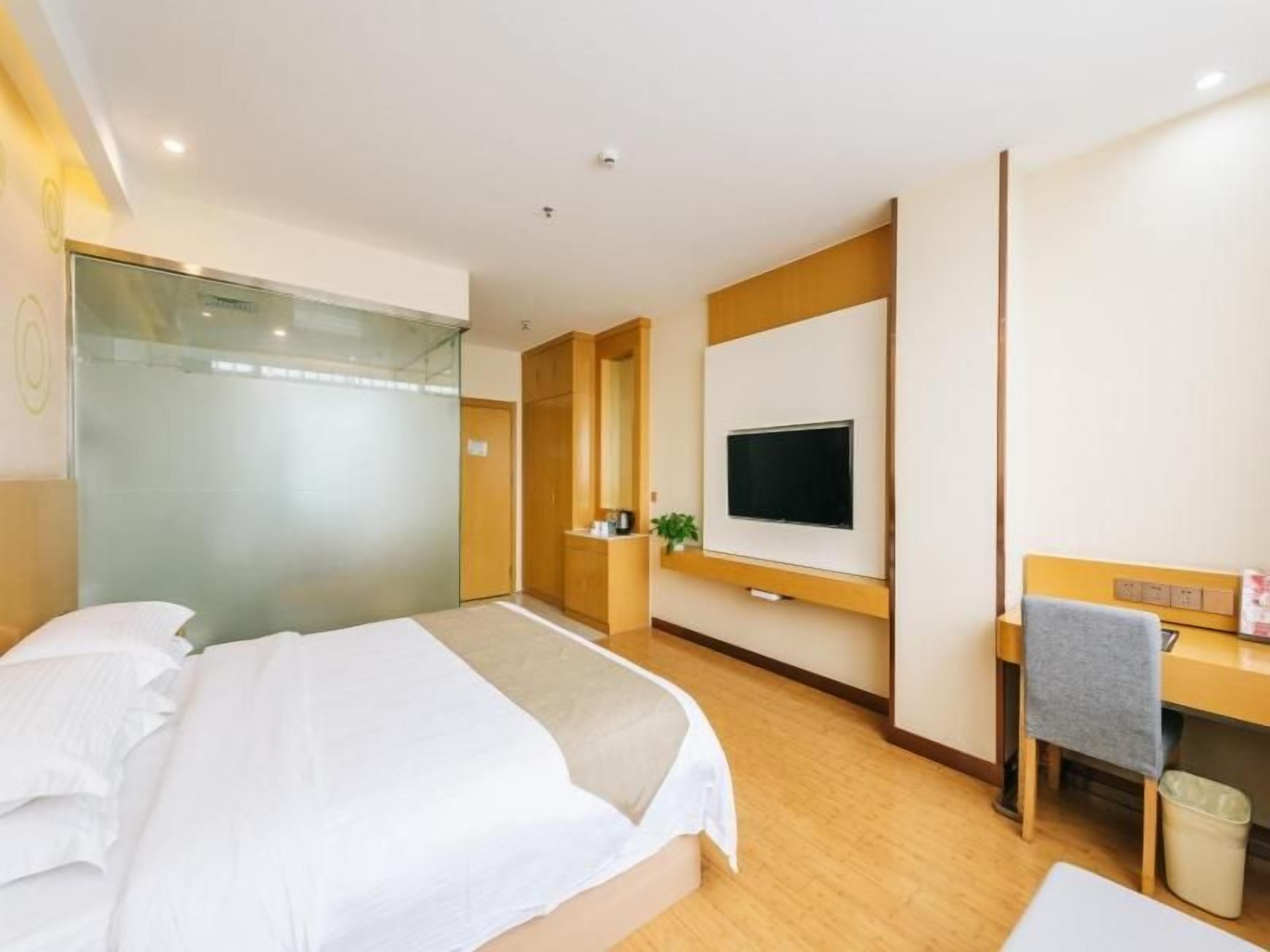 Una camera d'albergo con un letto, una scrivania, una televisione e uno specchio.