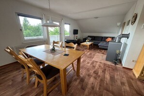 A dining area with a wooden table and chairs, a sofa, and a fireplace. - Apartment in Frankenau with swimming pool (Frankenau)