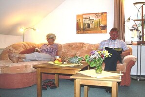 Ein Wohnzimmer mit einer Couch, einem Couchtisch und einem kleinen Tisch mit einem Blumenstrauß.