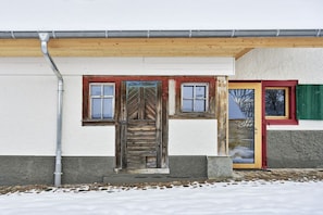 A building with a wooden door, a window, and a door with a green shutter. - Holiday apartment with 2 bedrooms (Löffingen)
