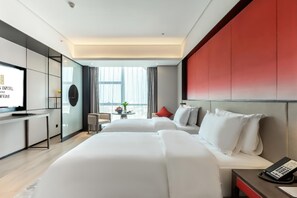 Habitación de hotel con dos camas, un escritorio, televisor, teléfono y vista a la ciudad.