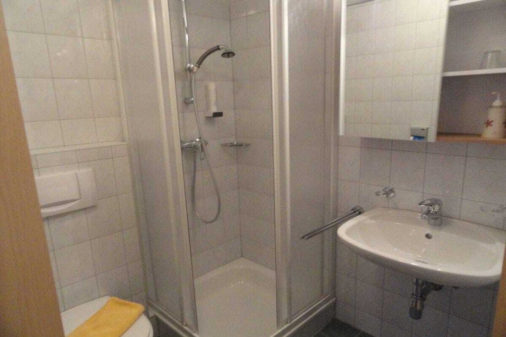 A bathroom with a glass-enclosed shower, a white sink, and a toilet.