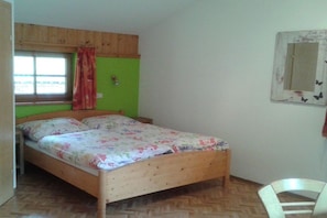 A single bed with a floral bedspread in a room with green walls and wooden flooring. - Holiday apartment with 2 bedrooms (Rauris)