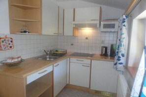 A compact kitchen with white cabinets, a microwave, a sink, and a small countertop. - Holiday apartment with 2 bedrooms (Rauris)