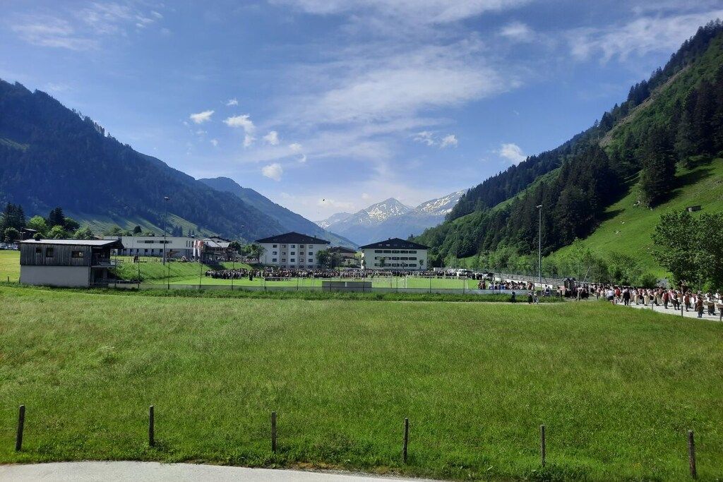 Eine gebirgige Landschaft mit Gebäuden und einer Menschenmenge.