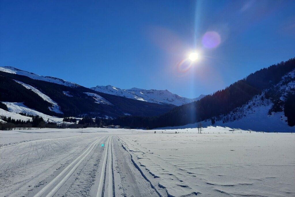 Un paisaje nevado con cielo despejado y sol radiante.