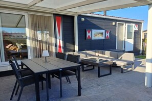 An outdoor patio with a dining table, chairs, and a sofa.