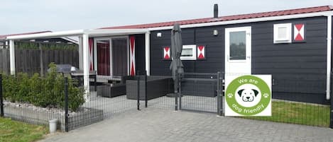 A dog-friendly establishment with a fenced outdoor area, a covered seating area, and a black exterior with red accents.