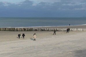 A beach with a wooden fence and people walking along the shore. - Cottage in Serooskerke with swimming pool (Serooskerke)