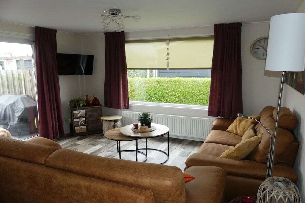 A living room with a sofa, a coffee table, a TV, and a window with curtains.