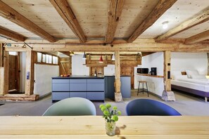 A rustic interior with exposed wooden beams, a central island with blue cabinetry, and a seating area with a table and chairs. - Holiday apartment with 2 bedrooms (Löffingen)
