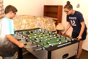 A foosball table in a room with a bed and a shelf in the background. - 2 Houses on the edge of the forest (Leutenbach)