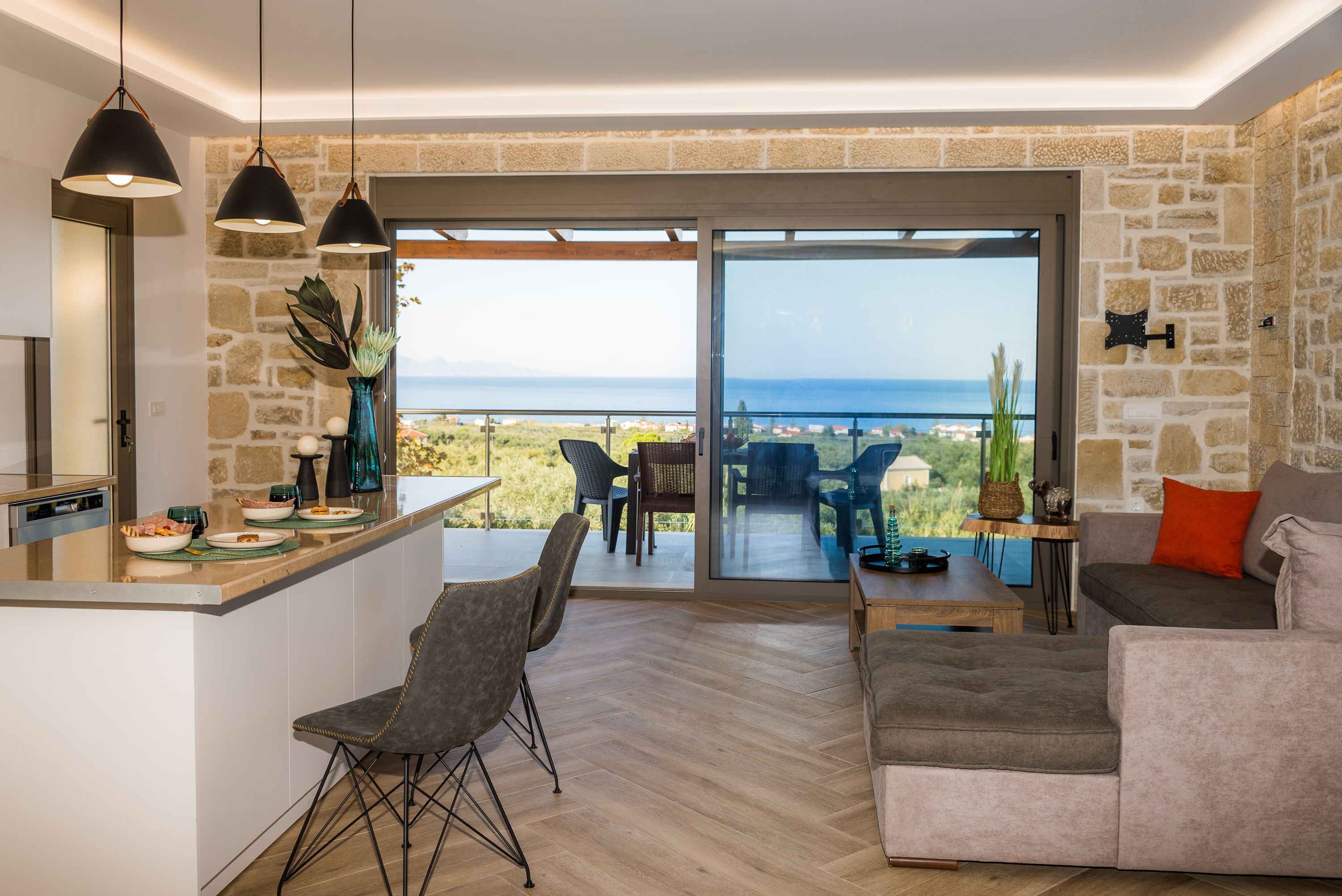 Ein moderner Wohnraum mit Küche, Essbereich und einem Balkon mit Meerblick.