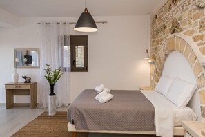 Ein Schlafzimmer mit einem Bett, einem Nachttisch, einem Spiegel, einer Vase mit Pflanzen und einer Steinwand.
