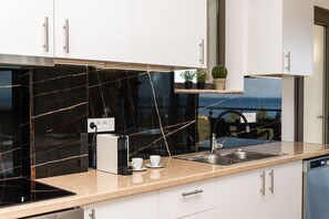 Eine moderne Küche mit schwarzem Marmor-Spritzschutz, Edelstahlgeräten und weißen Schränken.