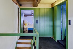 A staircase with green railings leading to a room with a bed and a small table. - Holiday apartment with 2 bedrooms (Löffingen)