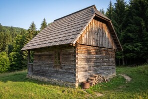 A rustic wooden cabin with a stone foundation, a single window, and a chimney.