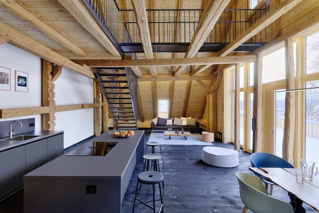 Un intérieur moderne comprenant une cuisine, un coin repas et un escalier menant à un niveau supérieur.