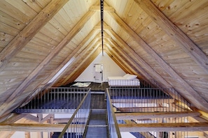 An attic bedroom with a wooden ceiling, a metal staircase, and a bed. - Holiday apartment with 2 bedrooms (Löffingen)