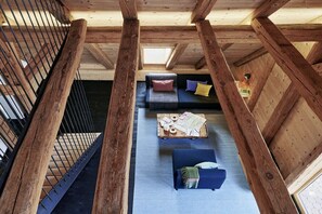 A loft-style room with a wooden ceiling, a staircase, a sofa set, and a coffee table with books and papers. - Holiday apartment with 2 bedrooms (Löffingen)