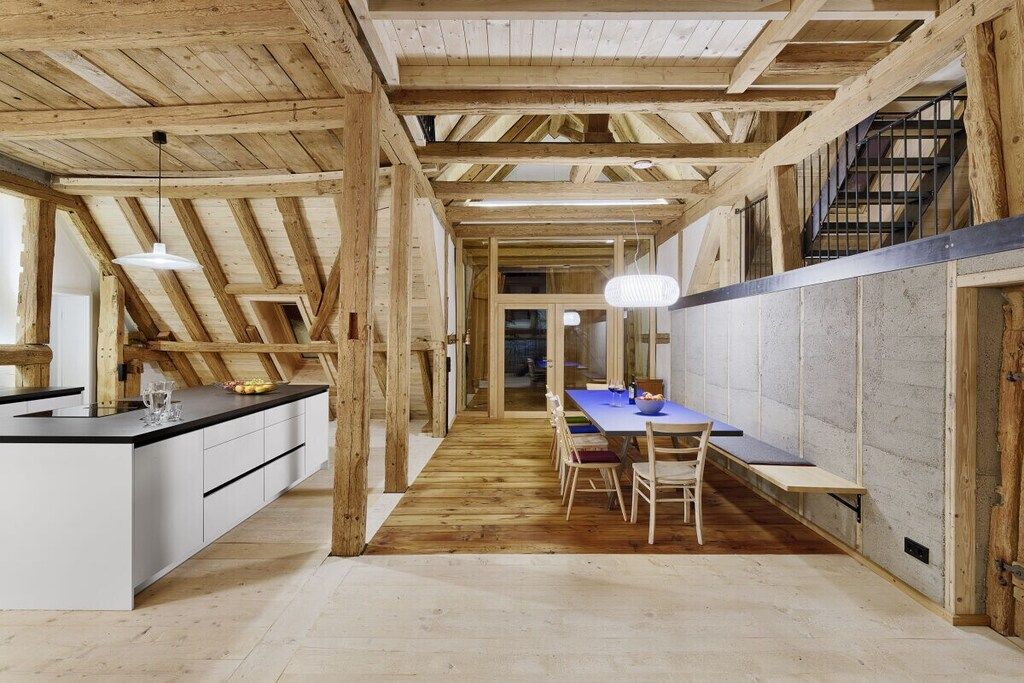 Una cocina con isla central, vigas de madera y un área de comedor con mesa y sillas.