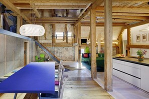 A spacious room with a large table, chairs, a staircase, and a kitchen area. - Holiday apartment with 3 bedrooms (Löffingen)