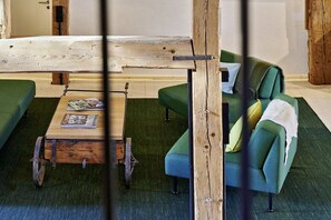 A room with a green sofa, a wooden coffee table, and a rustic wooden beam structure. - Holiday apartment with 3 bedrooms (Löffingen)