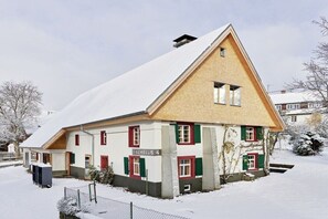 Un edificio cubierto de nieve con techo inclinado, un letrero que dice 'SCHELLIS 4' y un patio cercado.