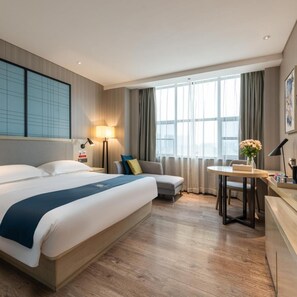 A hotel room with a large bed, a sofa, a dining table, and a view of the city through large windows. - Echarm Hotel (Guangzhou)