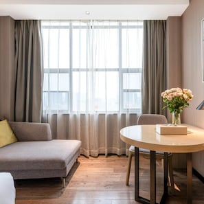 A modern living room with a sofa, a round table, and a vase of flowers. - Echarm Hotel (Guangzhou)