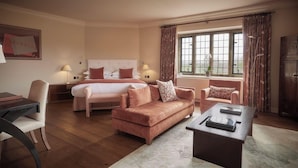 A hotel room with a bed, a sofa, a desk, and a window with curtains.