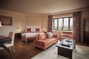 A hotel room with a bed, a sofa, a desk, and a window with curtains.